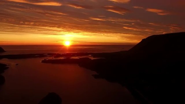 Aerial view of midnight sun casting red light over the ocean on island of Andoya in Norway. Aerial HD.