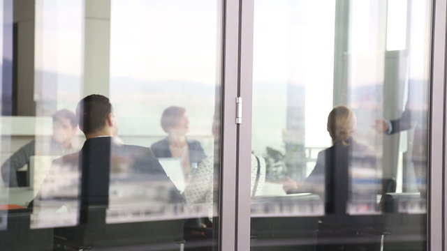 Colleagues on a meeting in conference room, behind glass wall