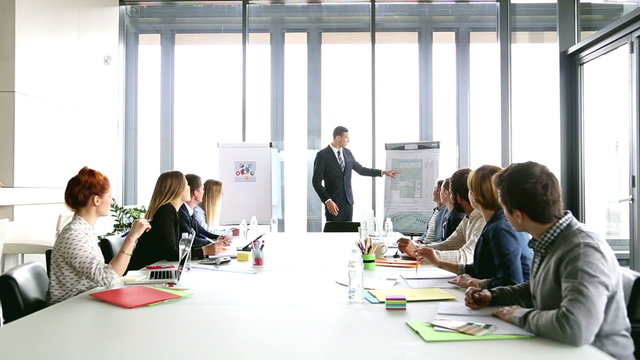 Handsome director pointing at flipchart during a meeting 