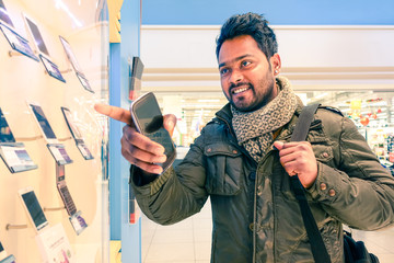 Young happy indian man pointing finger to showcase with mobile phones on display -Concept of human...
