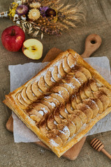 Homemade desserts. A composition with a pie, apples and herbs. Background of burlap