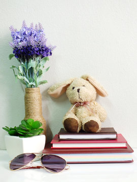 bunny rabbit doll sitting on notebook with artificial of green plant still life