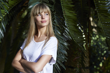 Blond beautiful woman by palm tree, looking away