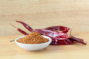 Chili powder and dried chili on wooden background, seasoning.