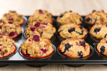 Fototapeta premium Black baking sheet with blueberry and raspberry cupcakes