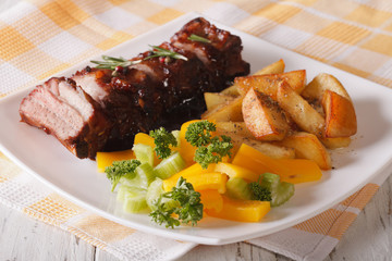 barbecue pork ribs with a side dish of vegetables and fried potatoes 

