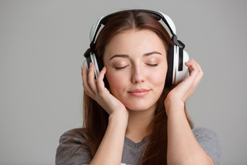 Pretty inspired young woman listening to music with eyes closed