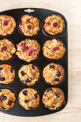 Black baking sheet with blueberry and raspberry cupcakes