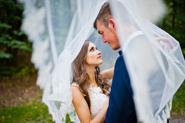 Young wedding couple under veil looking each other