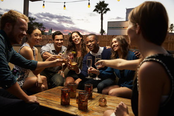 Group Of Friends Enjoying Night Out At Rooftop Bar