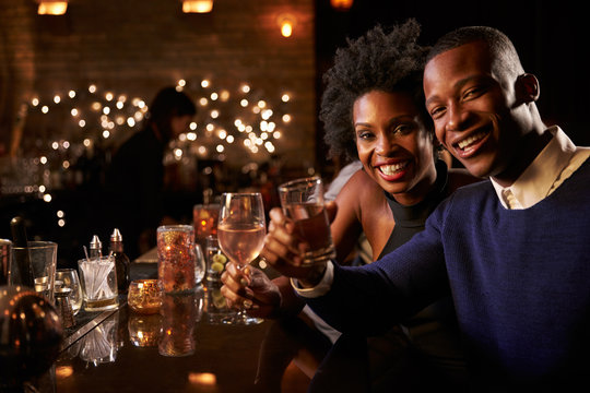 Portrait Of Couple Enjoying Night Out At Cocktail Bar