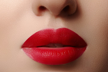 Close-up of woman's lips with fashion red make-up. Beautiful female mouth, full lips with perfect makeup. Classic visage. Part of female face. Macro shot of beautiful make up on full lips.