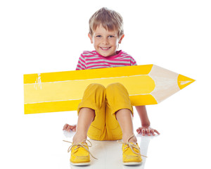 Happy kid with a big pencil in studio