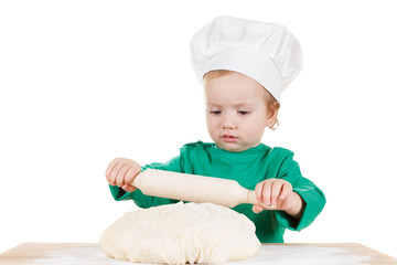serious little boy kneading dough for the cookies, isolated on white