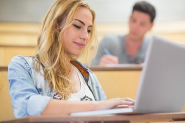 Smiling attractive student using laptop 