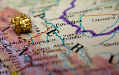 Close-up of a gold nugget on top of a map of Peru - obrazy, fototapety, plakaty