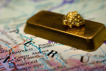 Close-up of a gold bar & nugget on top of a map of Peru