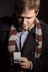 man with a pack of cigarettes and a cigarette in his mouth (at the bottom of the stack, the word...