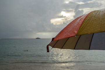 Colorful umbrella in the rain and blur beach background - 100715378