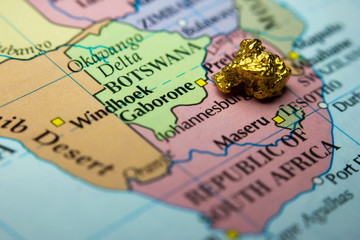 Close-up of a gold nugget on top of a map of South Africa