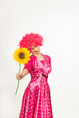 Cheerful, emotional clown in pink wig with yellow flower