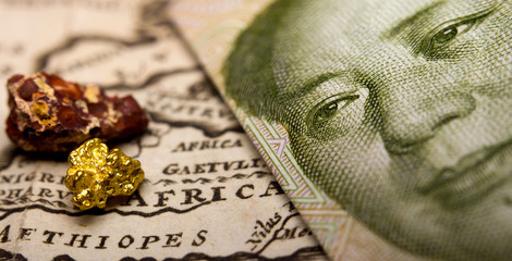 Close-up of a 1 yuan Chinese banknote (figuring Mao) and a gold nugget / rare earth metal on top of...