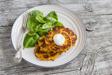 Pumpkin pancakes and fresh spinach on rustic light wooden table