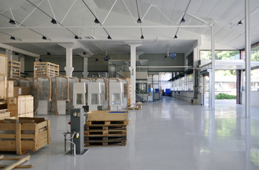Moderne, helle, Montagehalle oder Lagerhalle eines Unternehmens, in dem große, verpackte Produkte auf Paletten stehen.