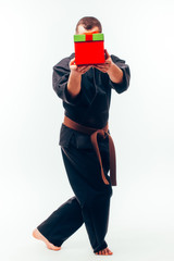 Young male  with orange belt karate fighter training with gift box. Isolated on white background