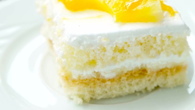 Cake with pineapple, closeup. Rotates on white plate.
