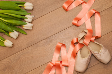 Ballet pointe shoes and white tulips on wooden background © litts