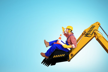 Builder in yellow helmet on the excavator