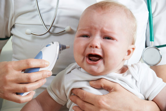 Nurse Taking Crying Baby's Temperature With Digital Thermometer