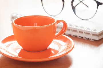 Close up of coffee cup with book and eyeglasses