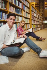 Smiling male student revising on floor