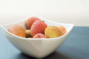 Bowl of fresh ripe lychees on a gray slate table top.