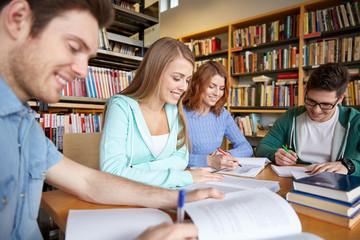 Fototapeta na wymiar happy students writing to notebooks in library