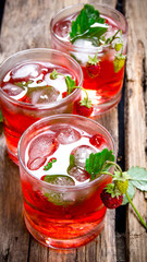 Cocktail of wild strawberries with ice on a wooden table.