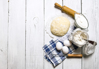 Preparation of the dough. Ingredients for the dough - flour, eggs, sour cream with a rolling pin and whisk.
