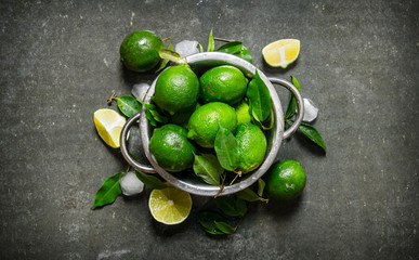 Lime background. Fresh limes in a saucepan with slices and leaves around.