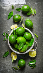 Lime background. Fresh limes in a saucepan with slices and leaves around.