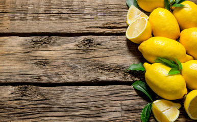 Fresh lemons with leaves. On wooden background.