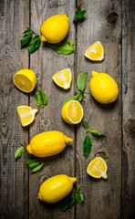 Lemons sliced and whole with leaves .