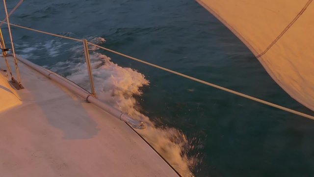 Sail boat plowing through water during sunset