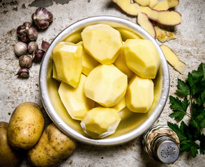 The concept of peeled potatoes in a bowl on the rustic background .