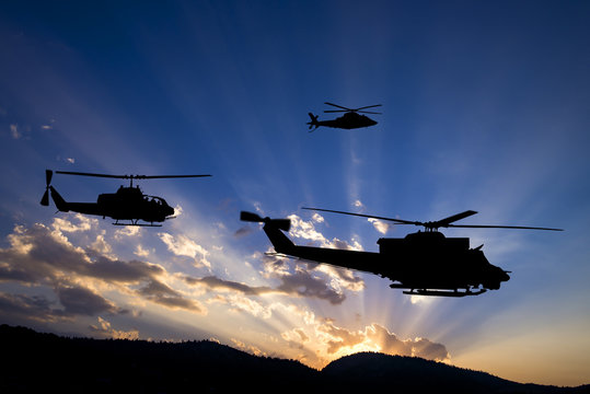Three flying army helicopters on sunset background

