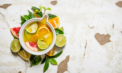 The juice from citrus fruits - grapefruit, orange, tangerine, lemon, lime in a cup with leaves.