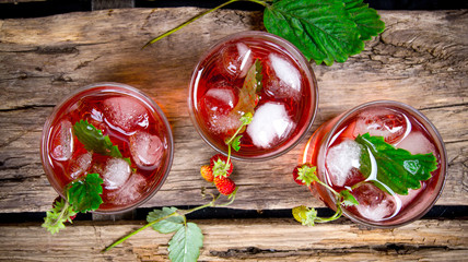 Cocktail of wild strawberries with ice on a wooden table.