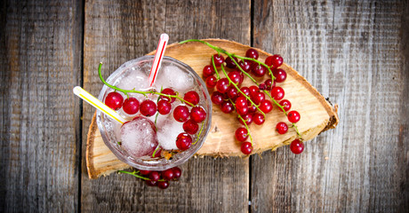 Cocktail of wild currant with ice on a wooden table.