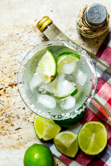 Ingredients cocktail - limes, ice , tequila, salt and liqueur on the old background .